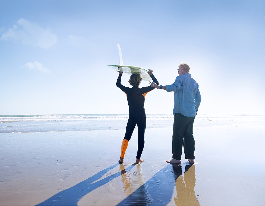 Grandfather and grandson on the beach with surfboard