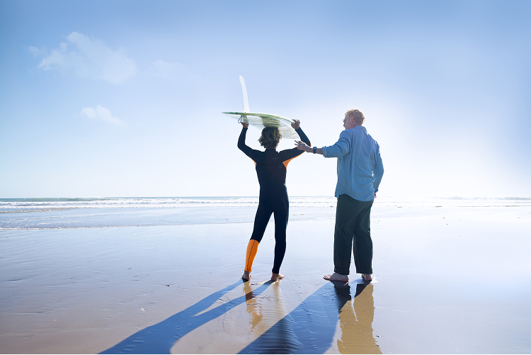 Grandfather and grandson on the beach with surfboard
