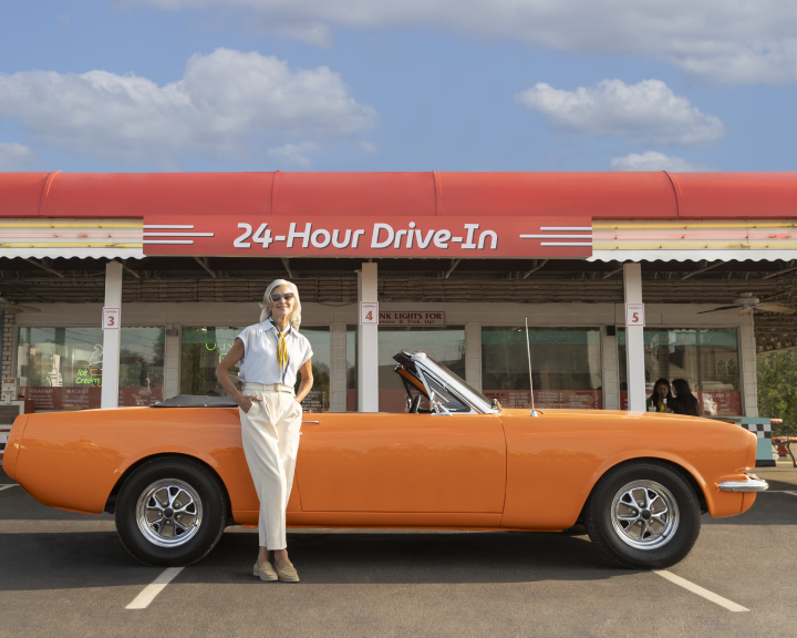 Woman standing in front of orange car