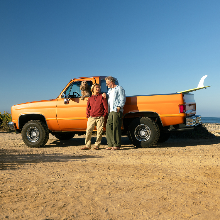 Grandfather and grandson standing in front of an orange pickup truck