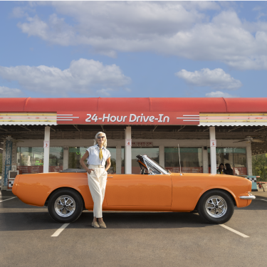 Woman standing in front of orange car