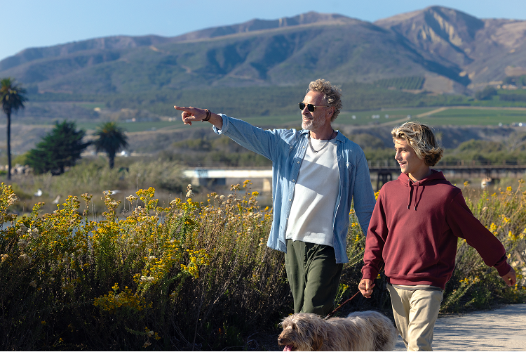 Grandfather and grandson walking dog